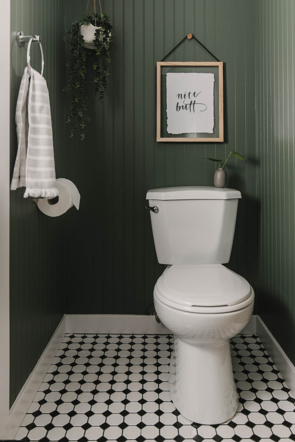 DIY green bathroom makeover with art over toilet and black and white tiled floors