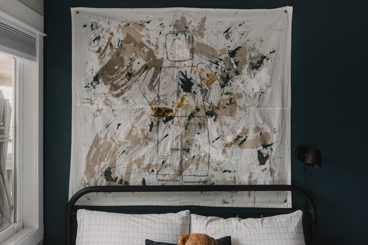 DIY Giant wall hanging on navy bedroom walls. Wall hanging has abstract paint and a line art lego man