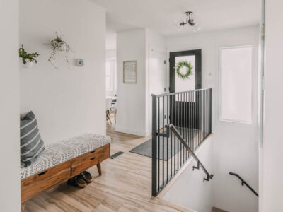 Bright white entry way makeover with black door and metal railing... plus that storage bench!