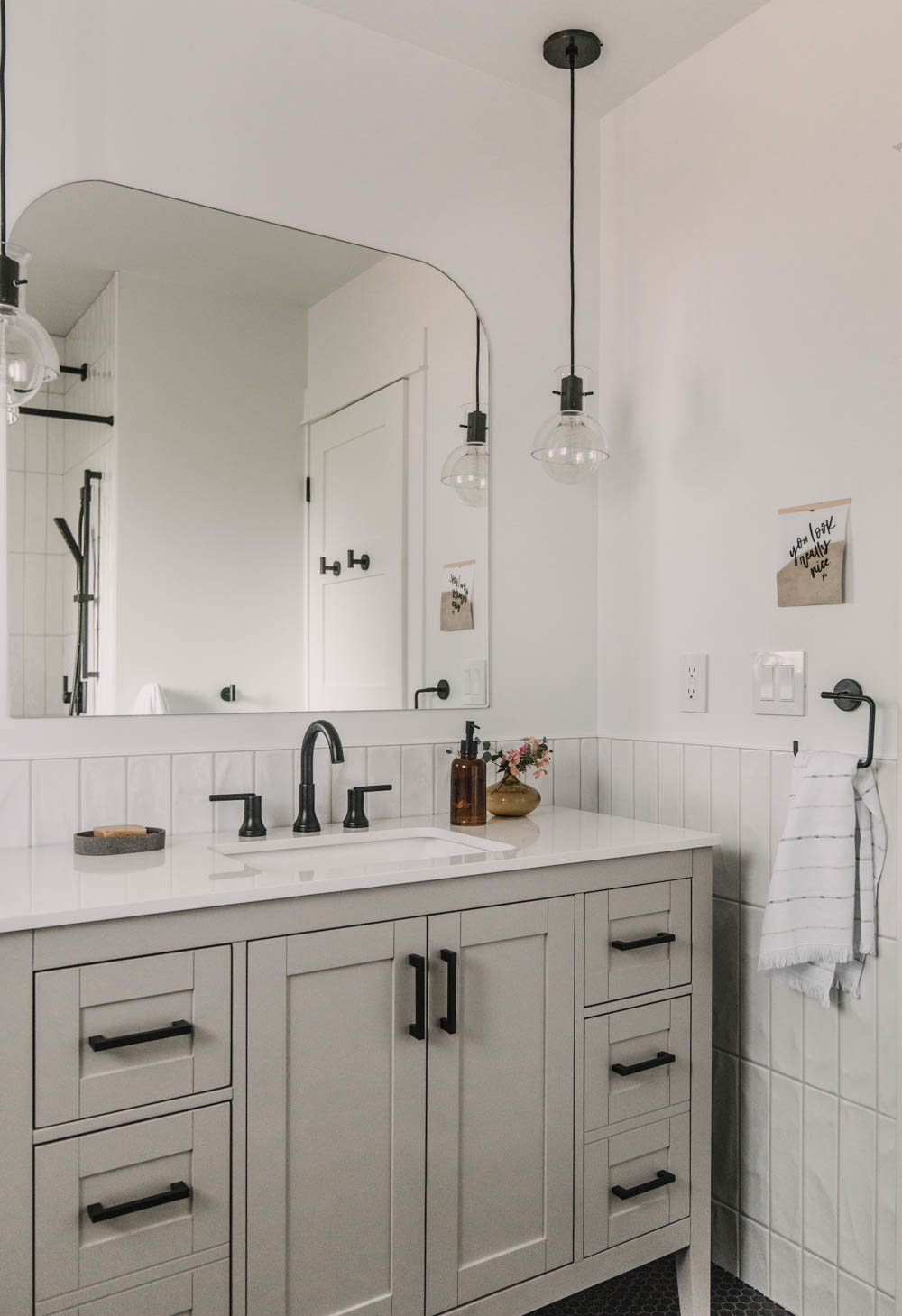 pendant lights with an arch mirror over the vanity