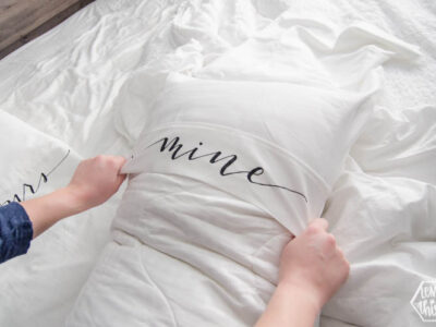 Putting on a king size pillow cover with the lettering 'mine'