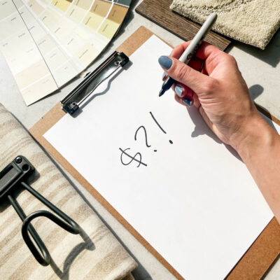 clipboard with dollar signs in sharpie, surrounded by room makeover supplies and samples