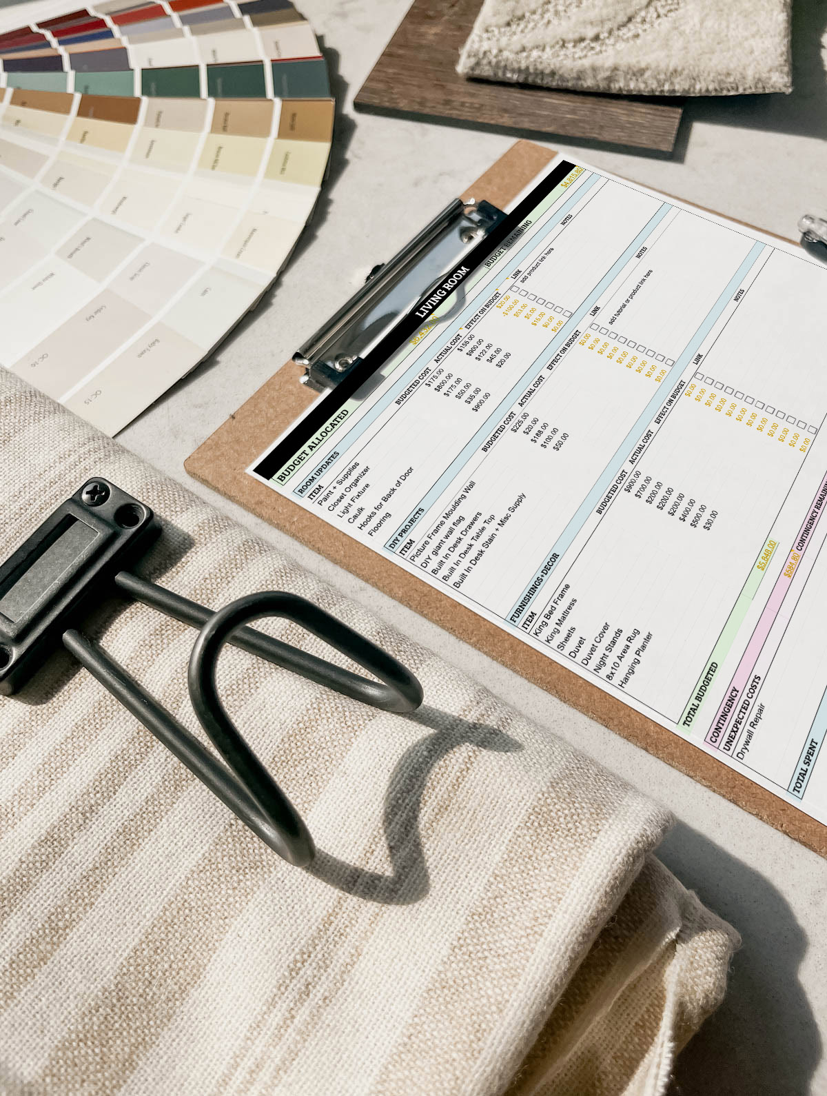 Free room makeover budgeting spreadsheet on clipboard surrounded by design samples