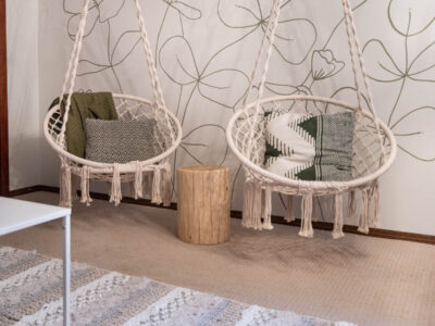 hanging chairs in front of a green floral line art mural