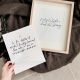 Free printable winter quotes shown printed on cardstock, one in wooden frame on cozy blanket