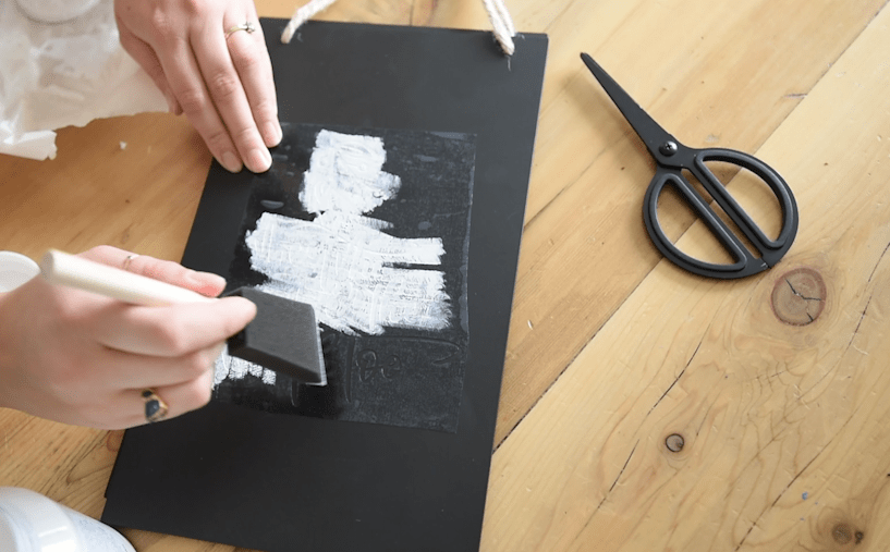 Dabbing paint on a stencil for a chalkboard effect